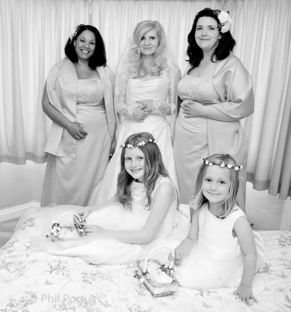 A black and white portrait shows a bride flanked by two bridesmaids and two flower girls.