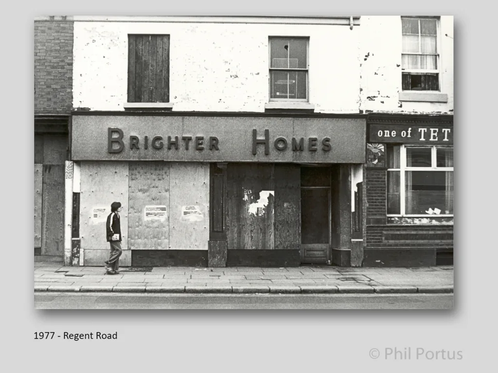 A black and white image shows a storefront with signage reading "Brighter Homes" and a person walking away.